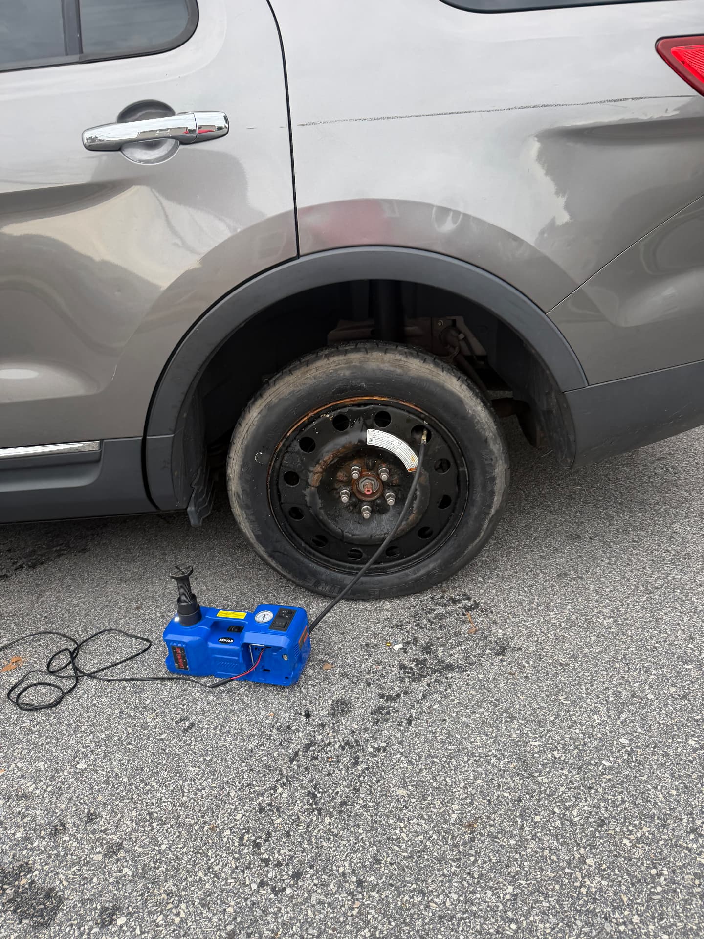 Spare wheel mounted and inflated on an SUV in a parking lot