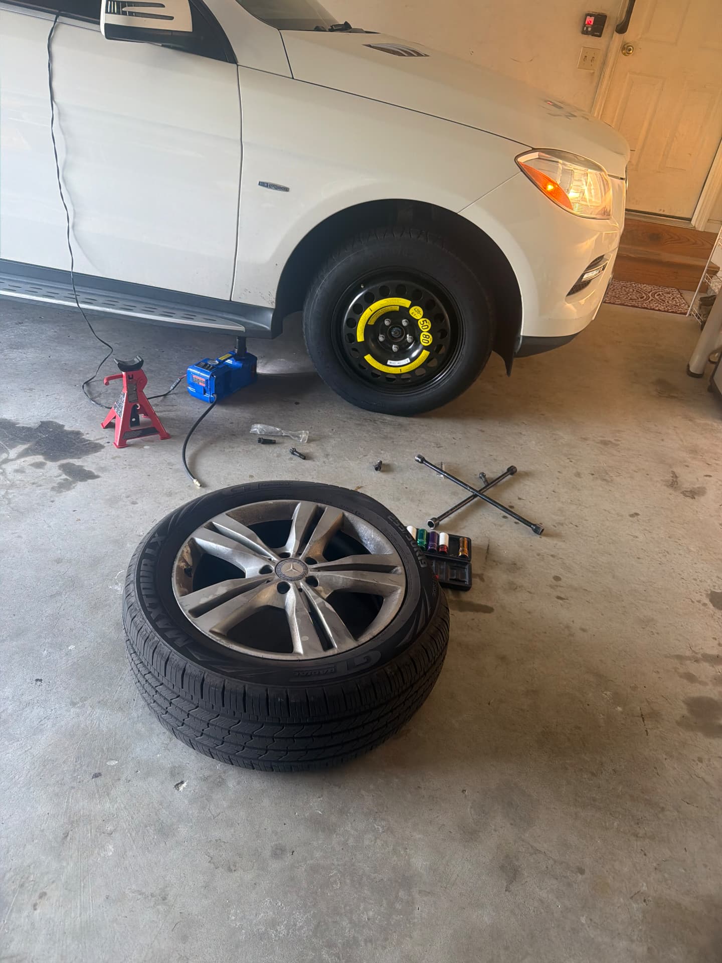 Mercedes SUV spare tire swap with jack stands in a garage