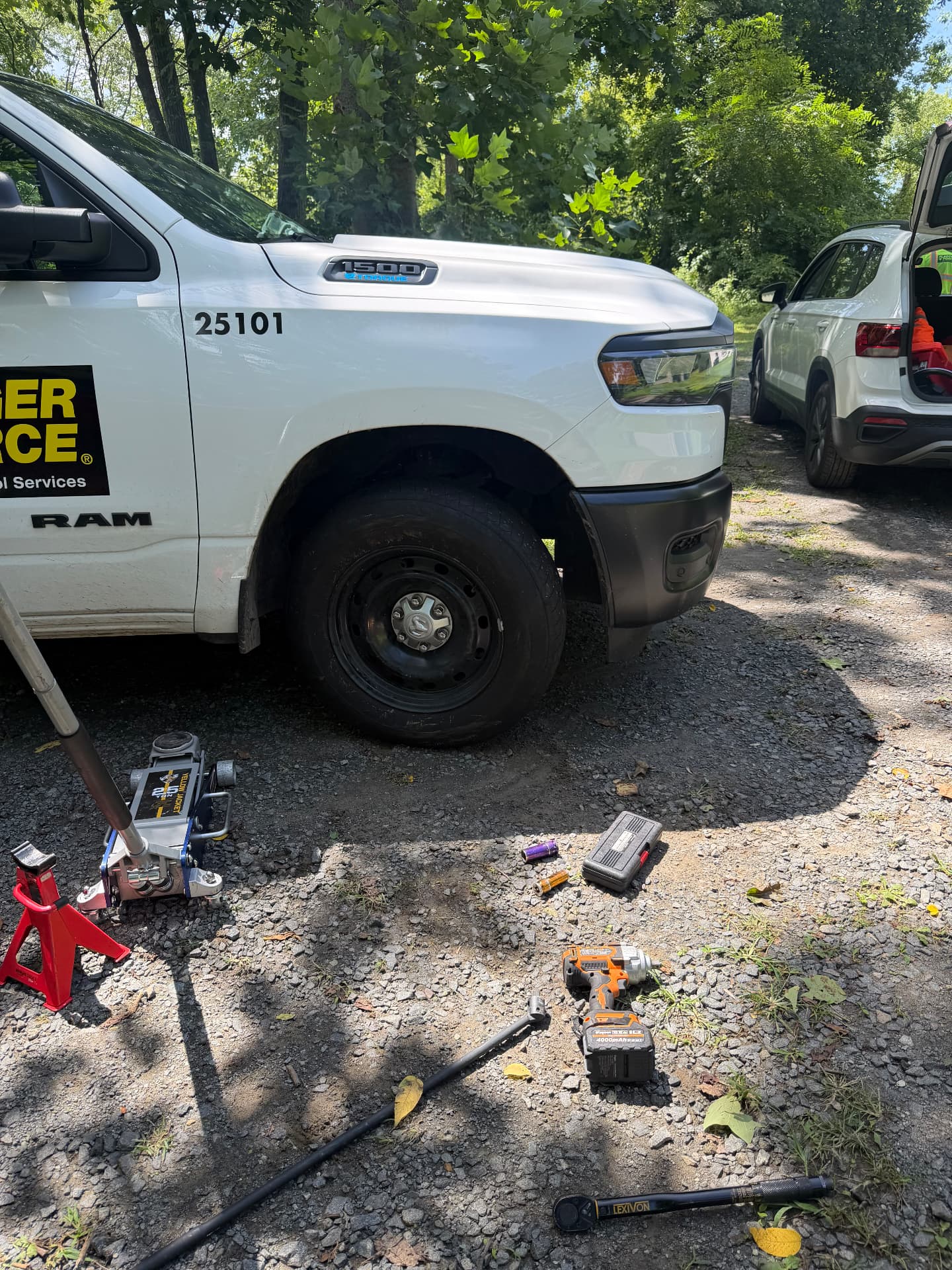 Roadside tire change on a Ram 1500 work truck with jack and impact wrench